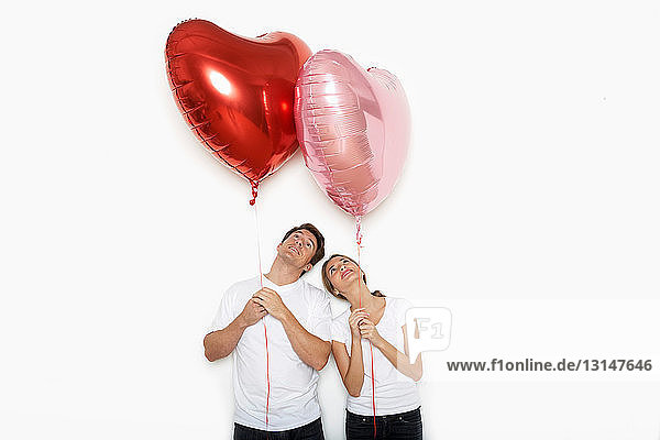 Paar hält Herzluftballons hoch