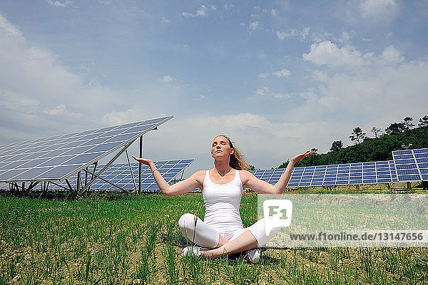 Frau macht Yoga vor einem Sonnenkollektor