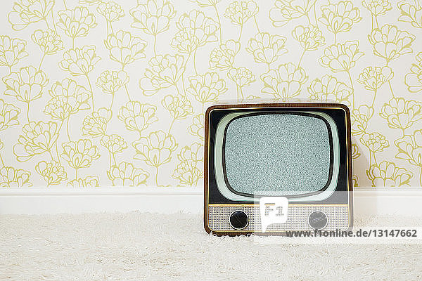 Retro television in room with patterned wallpaper