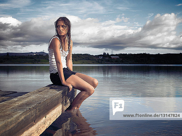 Woman sitting on dock by lake