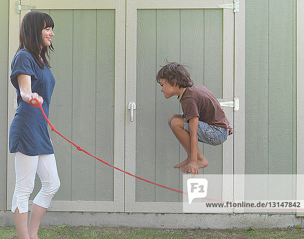 Kleiner Junge springt mit seiner Mutter Seil