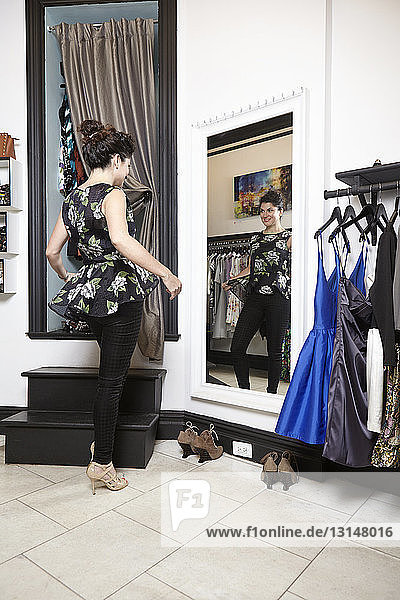 Ältere Frau in einer Modeboutique  die ihr Outfit im Spiegel betrachtet