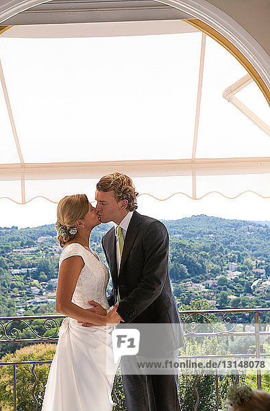 Braut und Bräutigam küssen sich auf dem Balkon
