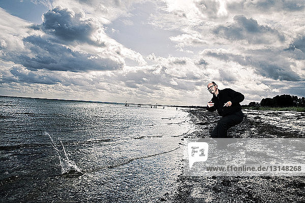 Man throwing stone in ocean  Koge Bay  Denmark
