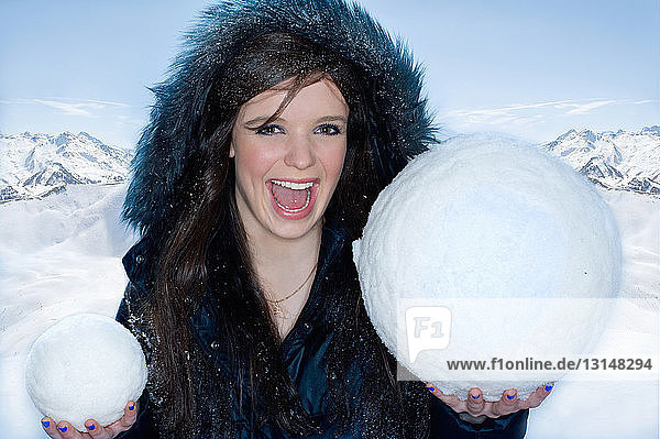 Junge glückliche Frau mit zwei Schneebällen