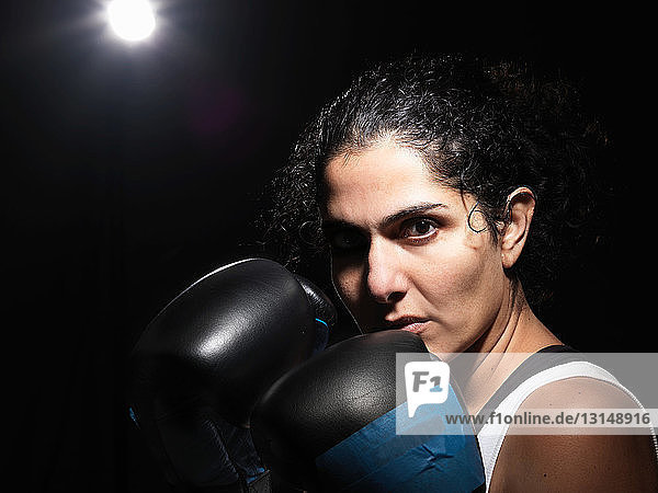 Portrait of female boxer against black background