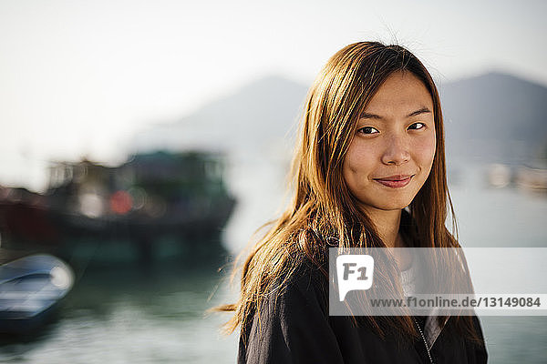 Porträt einer mittleren erwachsenen Frau vor Booten auf dem Wasser  die lächelnd in die Kamera schaut
