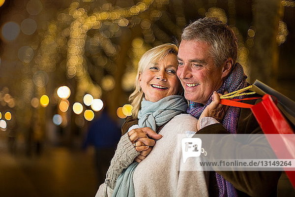 Portrait of mature couple with xmas shopping on tree lined avenue  Majorca  Spain