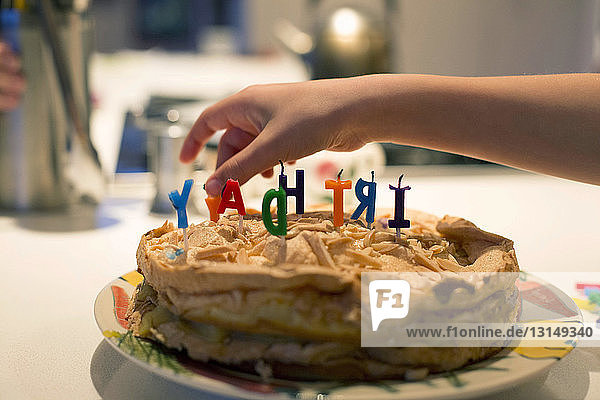 Jungenhand entfernt Geburtstagskerzen vom Kuchen
