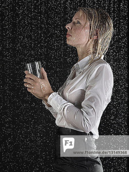 Businesswoman collecting rain in glass