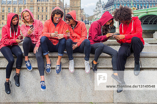 Kleine Gruppe junger Menschen  die Informationen über Mobiltelefone austauschen