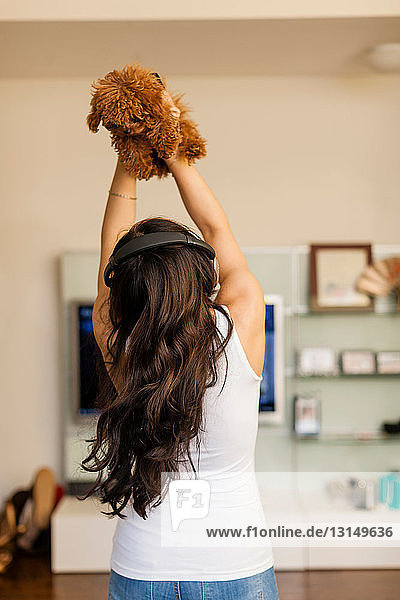 Mid adult woman wearing headphones and dancing with dog