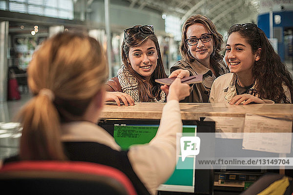 Frau und zwei Teenager-Mädchen beim Check-in am Flughafen