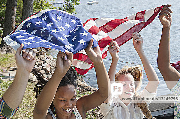 Freunde halten lächelnd die US-Flagge über dem Kopf