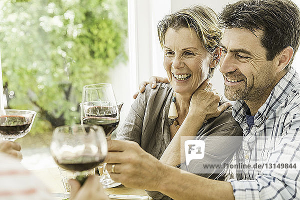 Couple toasting with red wine at dining table