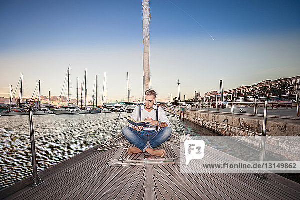 Young man reading on yacht  Cagliari  Sardinia  Italy