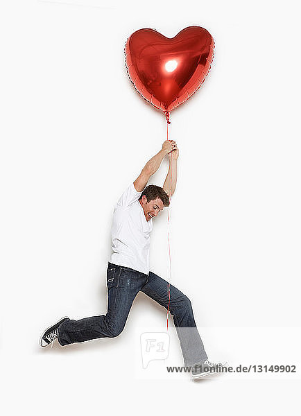 Mann wird von Herzballon hochgehoben