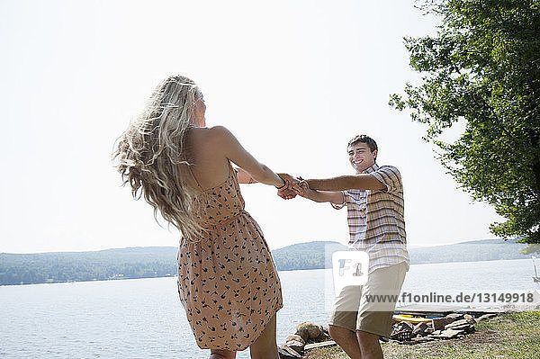 Junges Paar hält Hände am See