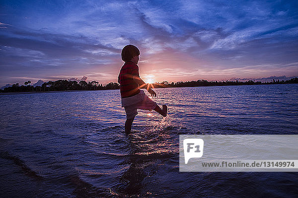 Young boy paddling in sea  sunset