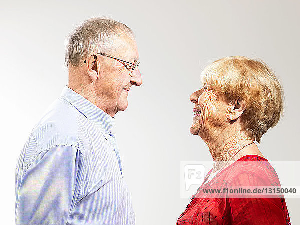 Senior couple standing face to face against white background