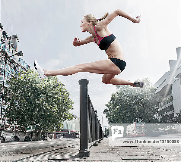Sportler springt über Geländer auf Straße