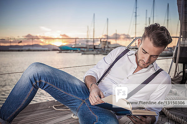 Young man reading on yacht  Cagliari  Sardinia  Italy