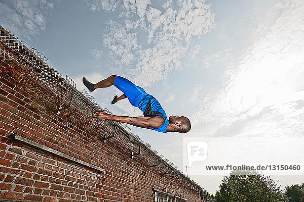 Sportler springt über eine Mauer
