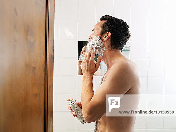 Mature man applying shaving foam in bathroom