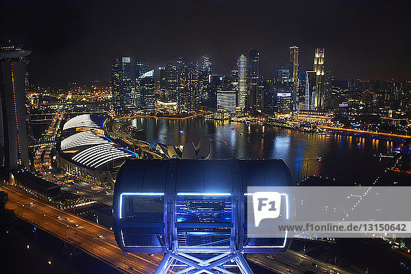 View of skyscrapers on waterfront from ferris wheel at night  Singapore