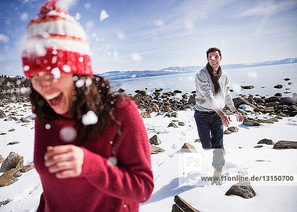 Man throwing snowball at woman