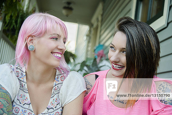Zwei flippige Freundinnen unterhalten sich auf der Veranda