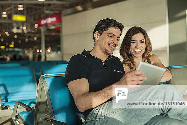 Junges Paar benutzt digitales Tablet in der Abflughalle eines Flughafens