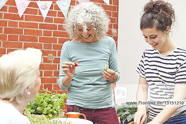 Drei Frauen bereiten am Gartentisch frische Lebensmittel zu