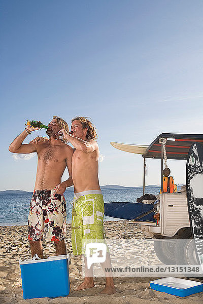 Junge Männer am Strand trinken Bier mit dem Jeep