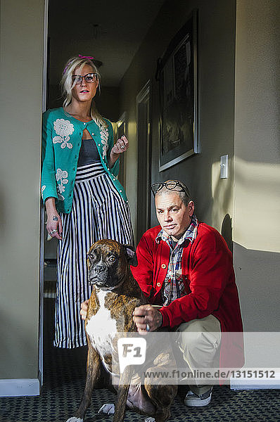 Couple in hallway with boxer dog looking at camera