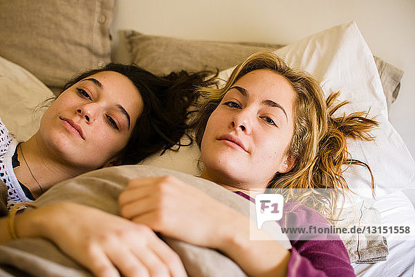 Portrait of two young woman lying in bed