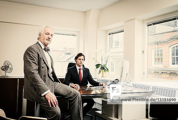 Junger Geschäftsmann am Schreibtisch mit älterem Mann im Büro