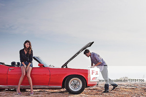 couple standing at car with opened hood