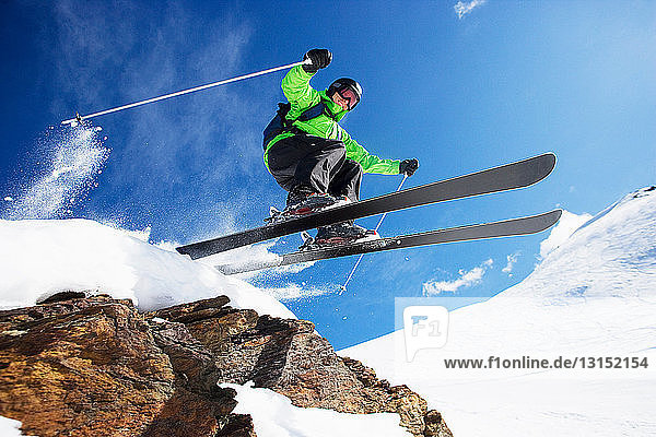 Male skier jumping at speed down mountain