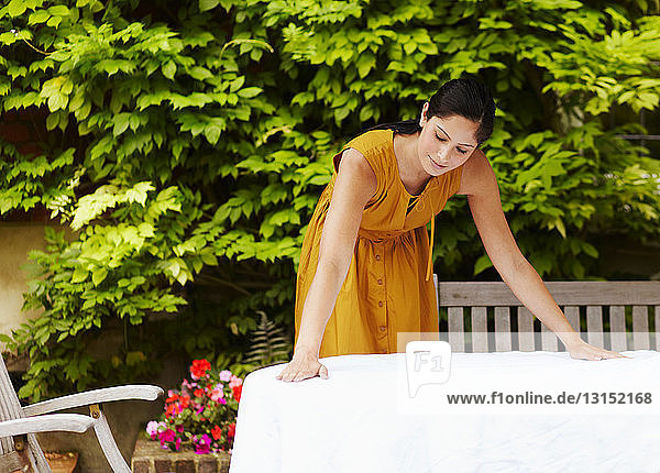 Frau breitet Tischtuch im Freien aus