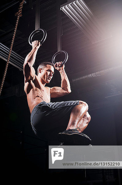 Man using suspended rings in gym