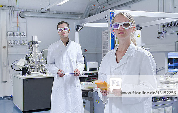 Zwei Wissenschaftler in Laborkitteln und mit Schutzbrille stehen in einem Labor
