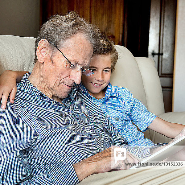 Großvater und Enkel schauen auf ein digitales Tablet