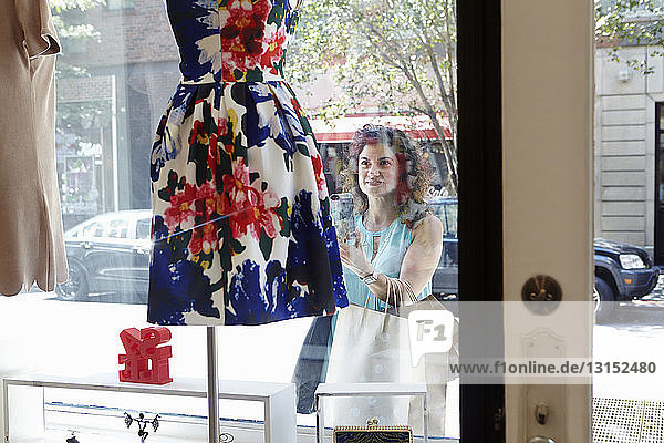 Ältere Frau schaut in das Schaufenster einer Modeboutique