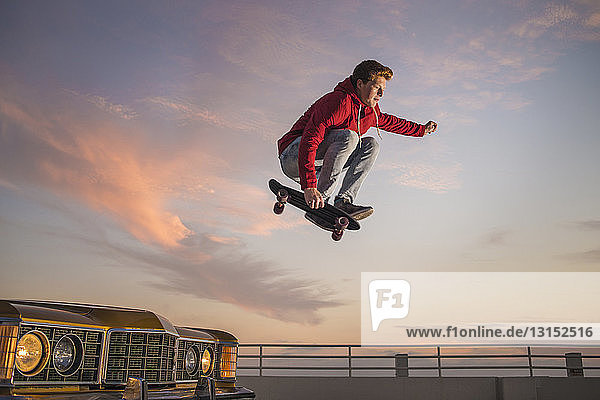 Porträt eines jungen Mannes auf einem Skateboard in der Luft