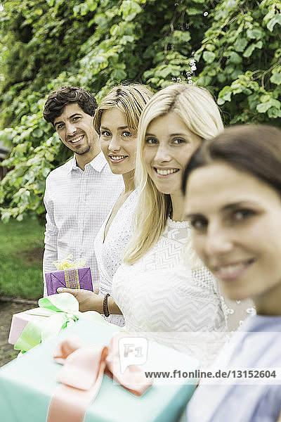 Porträt eines jungen Mannes und dreier Frauen mit Geburtstagsgeschenken im Garten