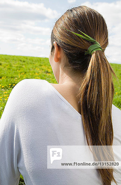 Frau mit ins Haar gebundenem Gras