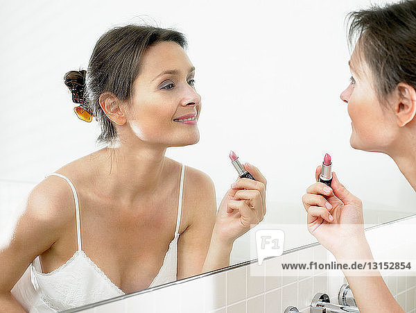Woman in bathroom  applying makeup