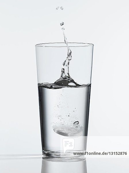 Tablette spritzt in ein Glas mit Wasser