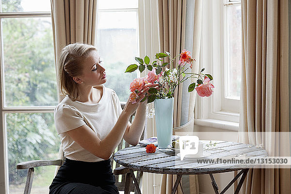 Frau arrangiert Rosen in einer Vase